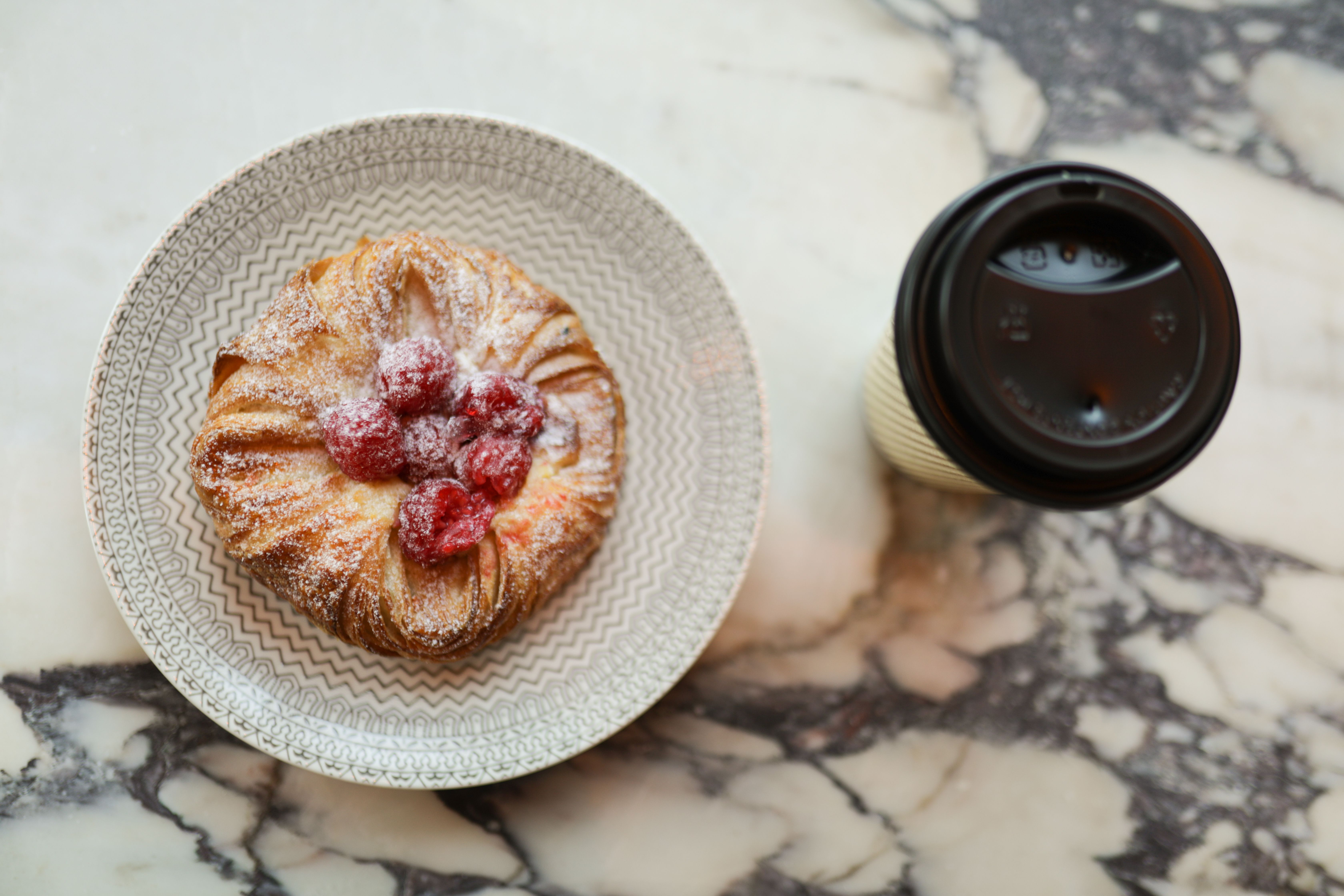 Pastry on a plate and coffee in a to-go cup