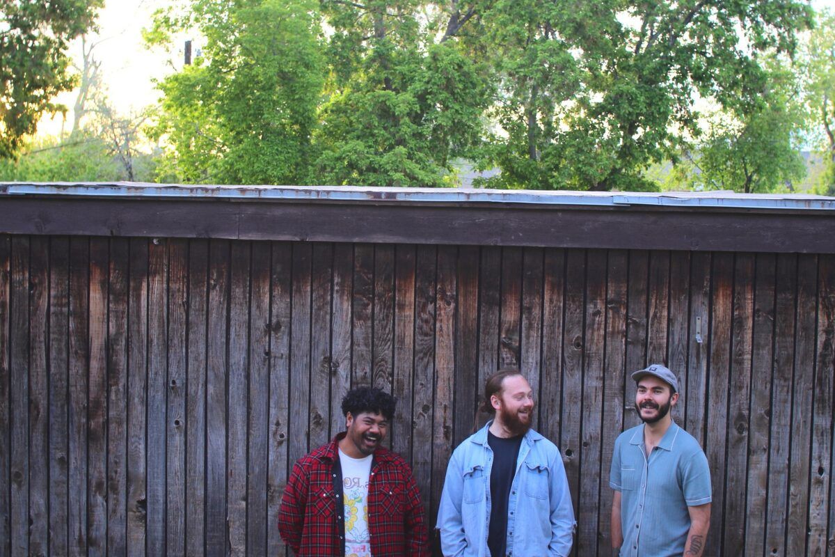 three men in front of fence