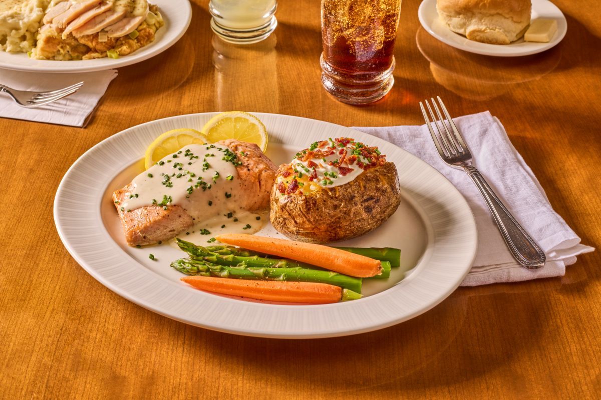 Plate of food that includes salmon, baked potato, and vegetables
