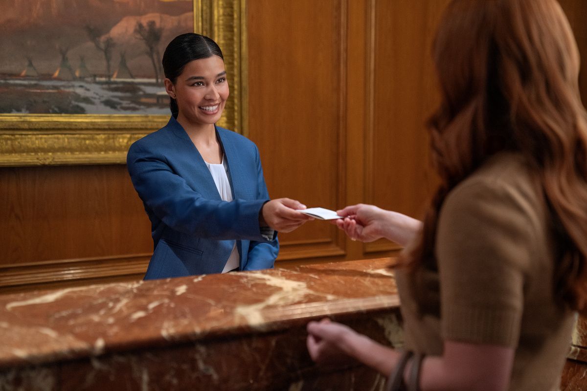 Receptionist handing a hotel card to a woman